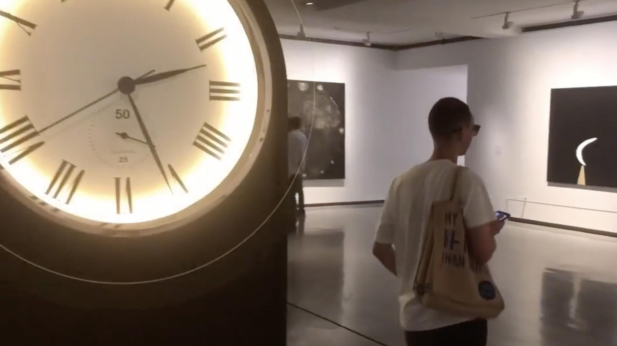 Someone with earphones walking in a Gallery with phone in hand