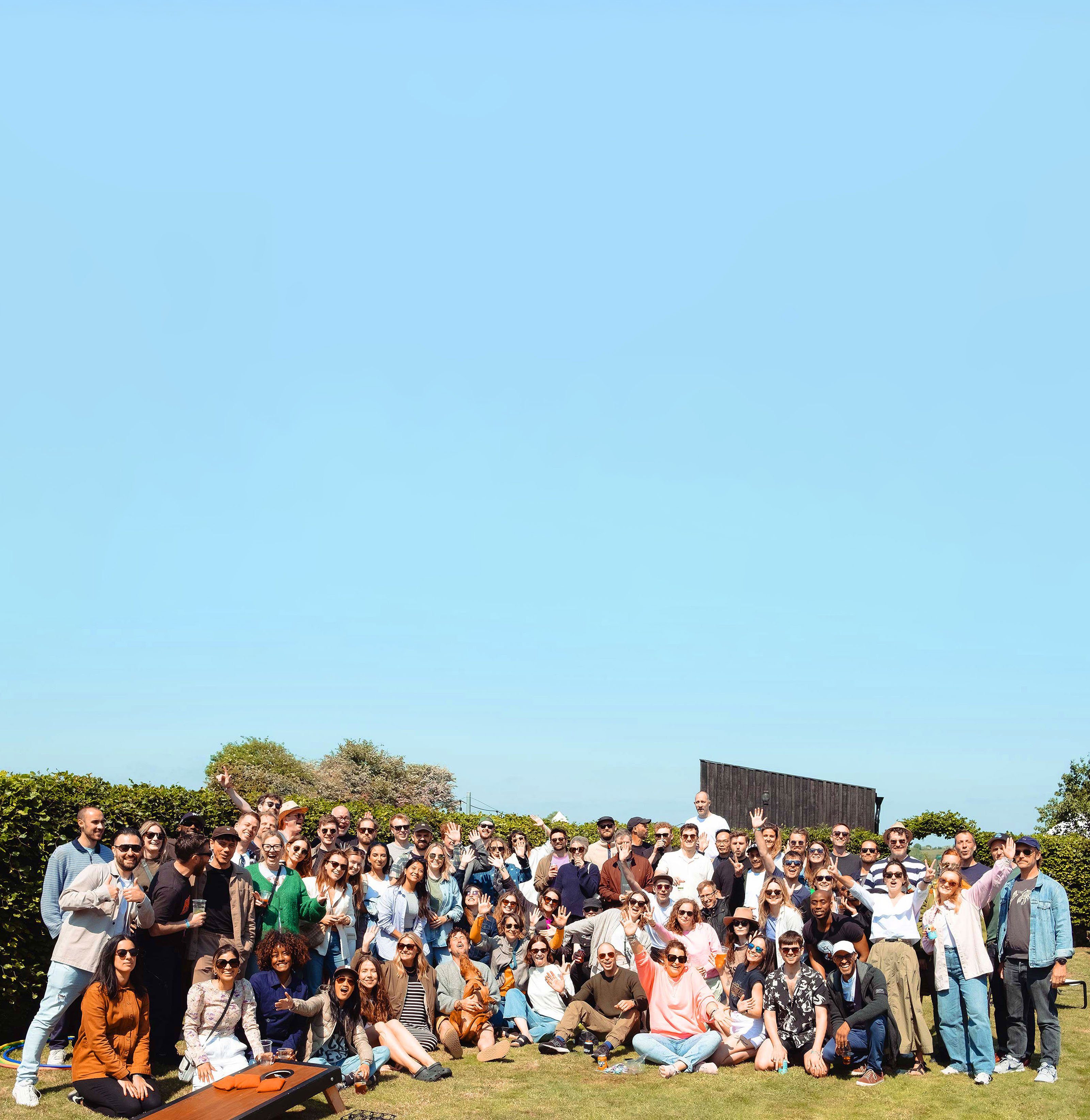 A group photo of employees at our annual social day, smiling, waving and cheering